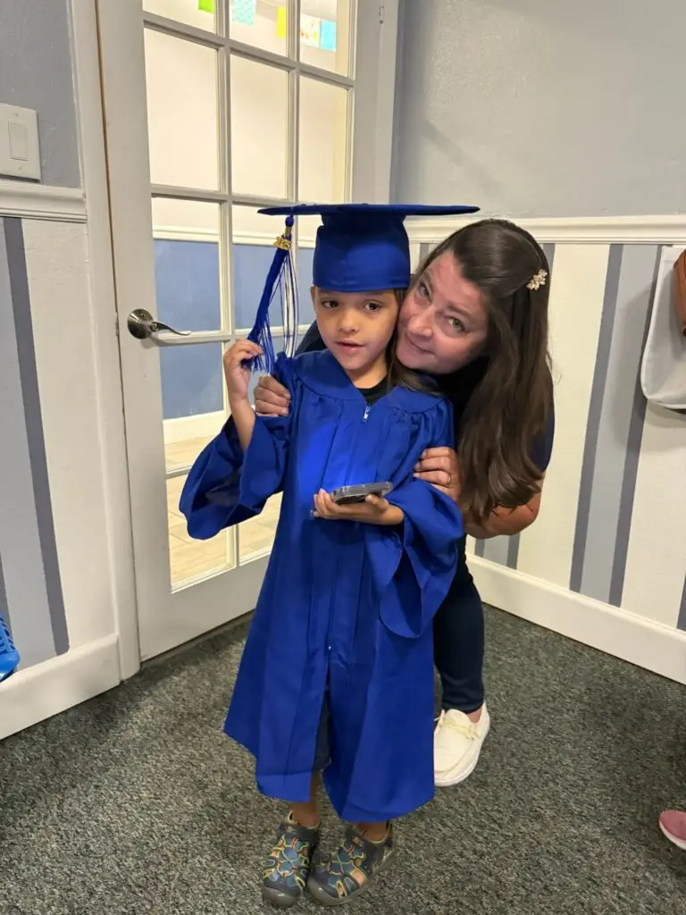 Preschool graduate in cap and gown with teacher at Bethany Christian Preschool in West Melbourne, FL, celebrating learning and family partnership.