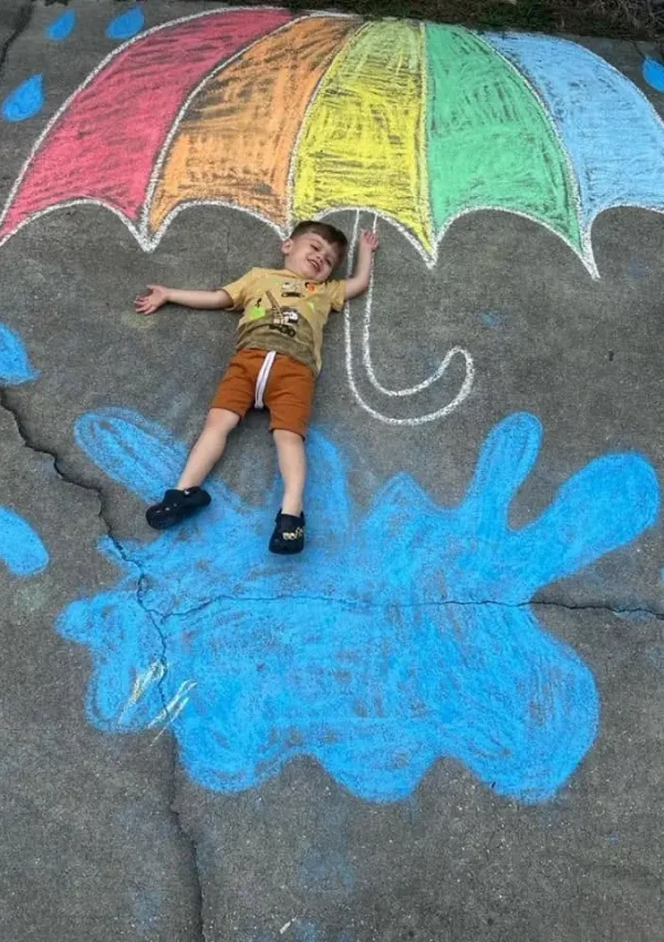 Bethany Christian Preschool child playing under colorful chalk umbrella art in West Melbourne, FL